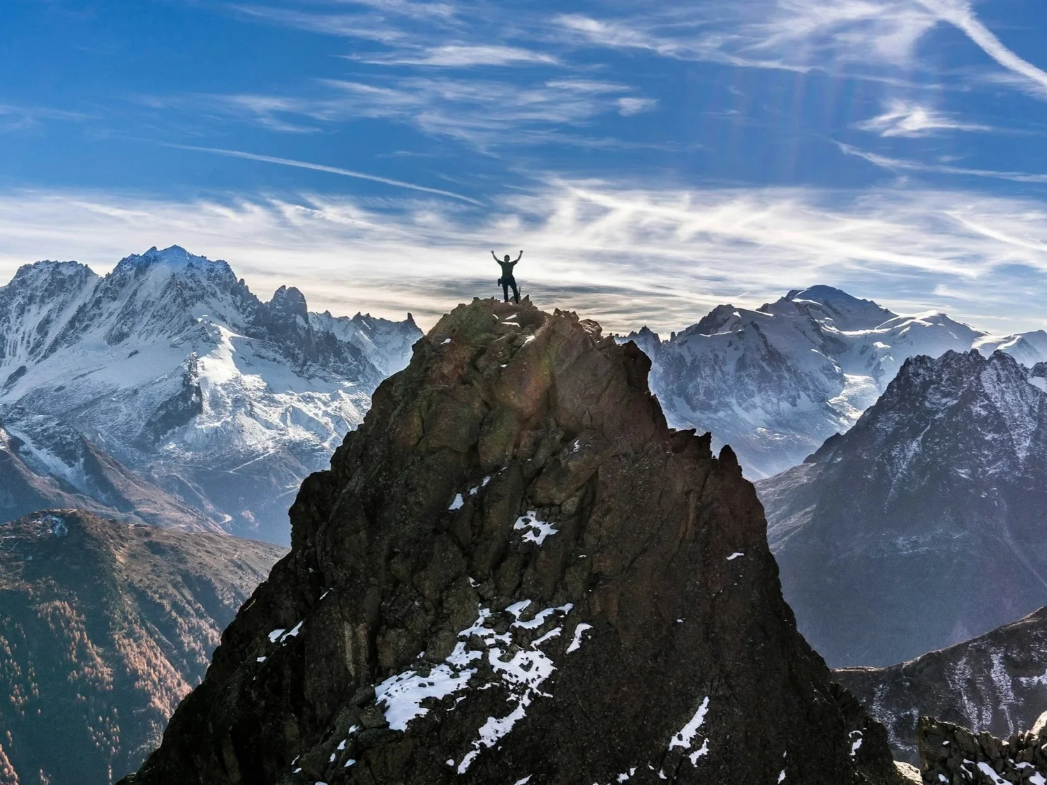 A person standing at the summit of a mountain ridge